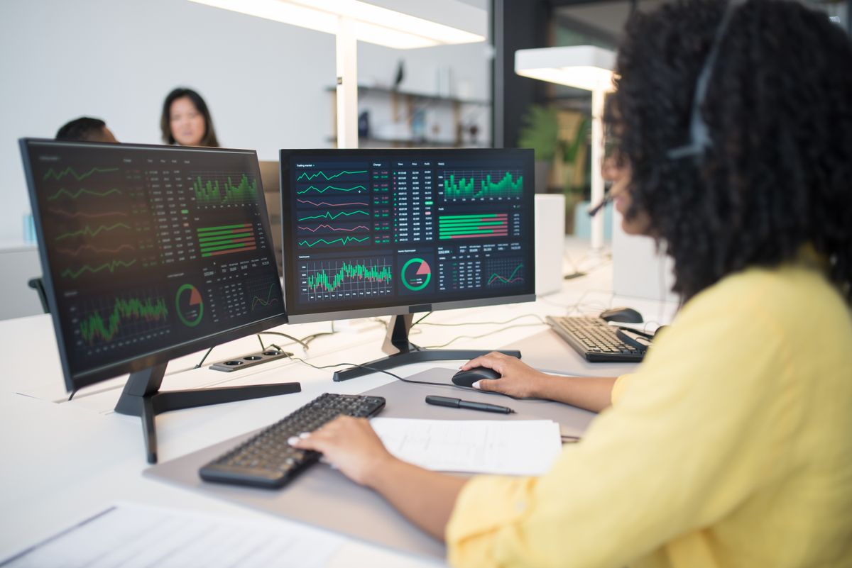 An analyst reviewing data dashboards on dual monitors