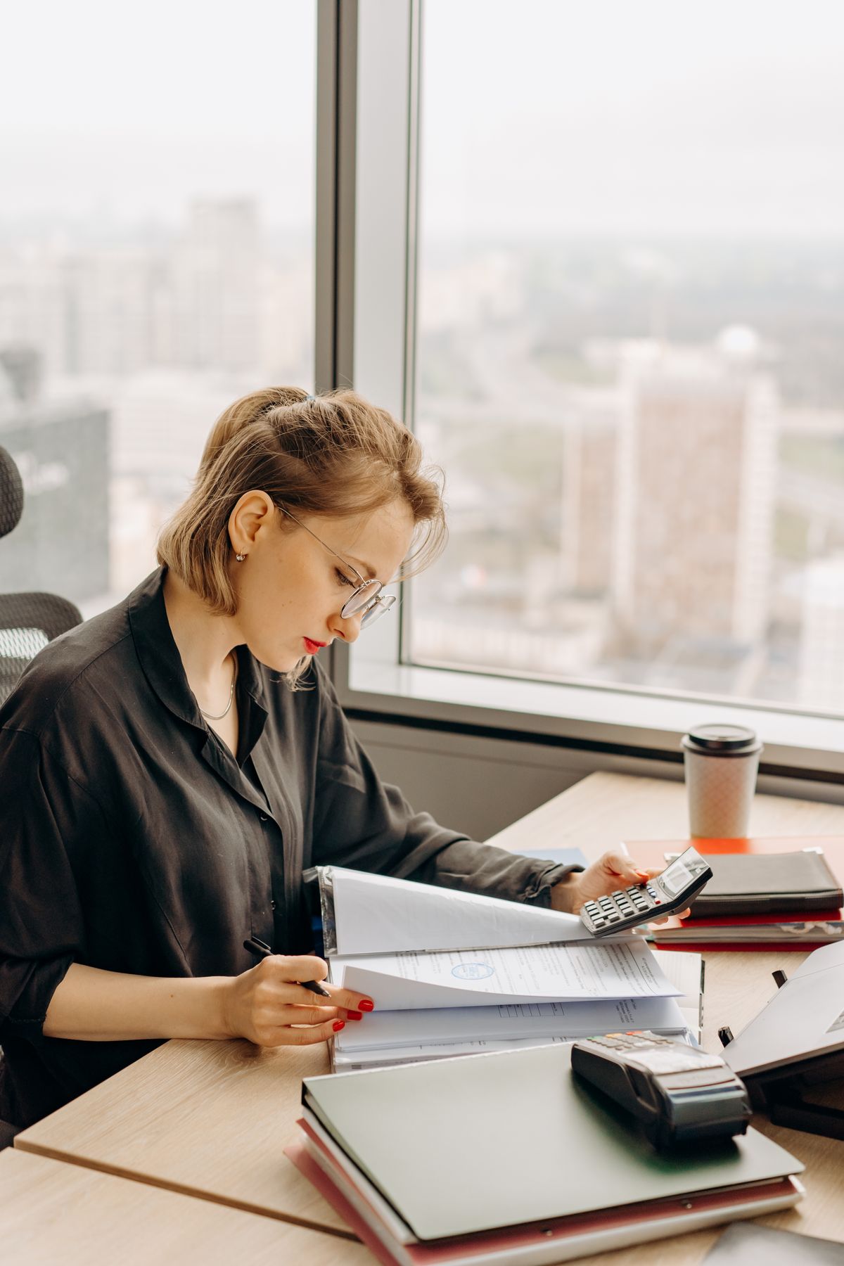 A finance professional reviewing figures by a city-view window
