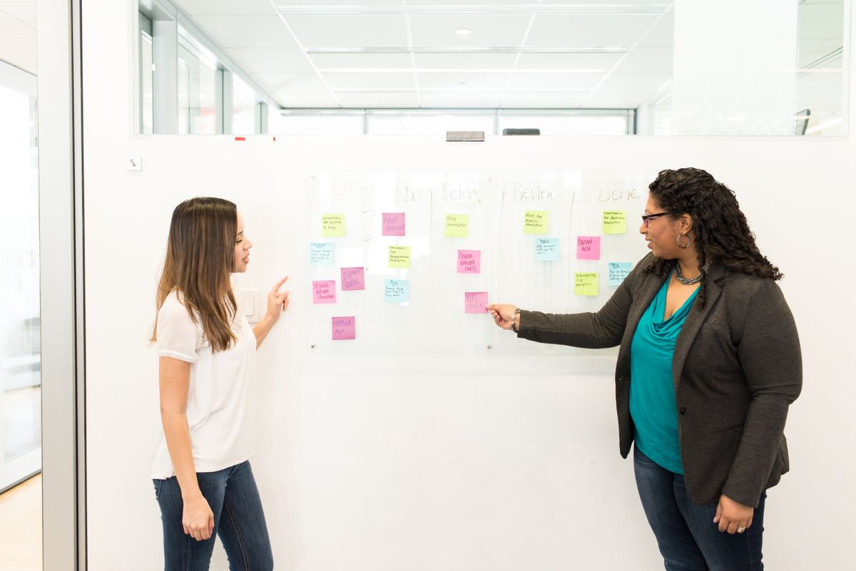 Two colleagues planning at a whiteboard with sticky notes